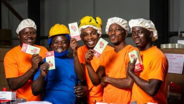 Arbeiter in einer Fabrik in Ghana präsentieren nachhaltig produzierte Schokolade von Fairafric.