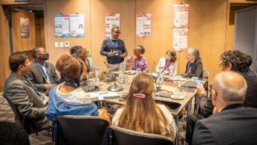 Einige Teilnehmer des Global Forum diskutieren an einem kleinen Tisch auf dem Netzwerktreffen in Kapstadt.