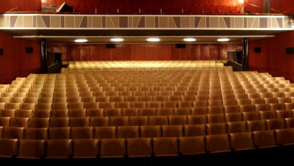 Der Zuschauerraum des Gloria-Theaters mit vielen Stühlen in vielen Reihen und Beleuchtung.
