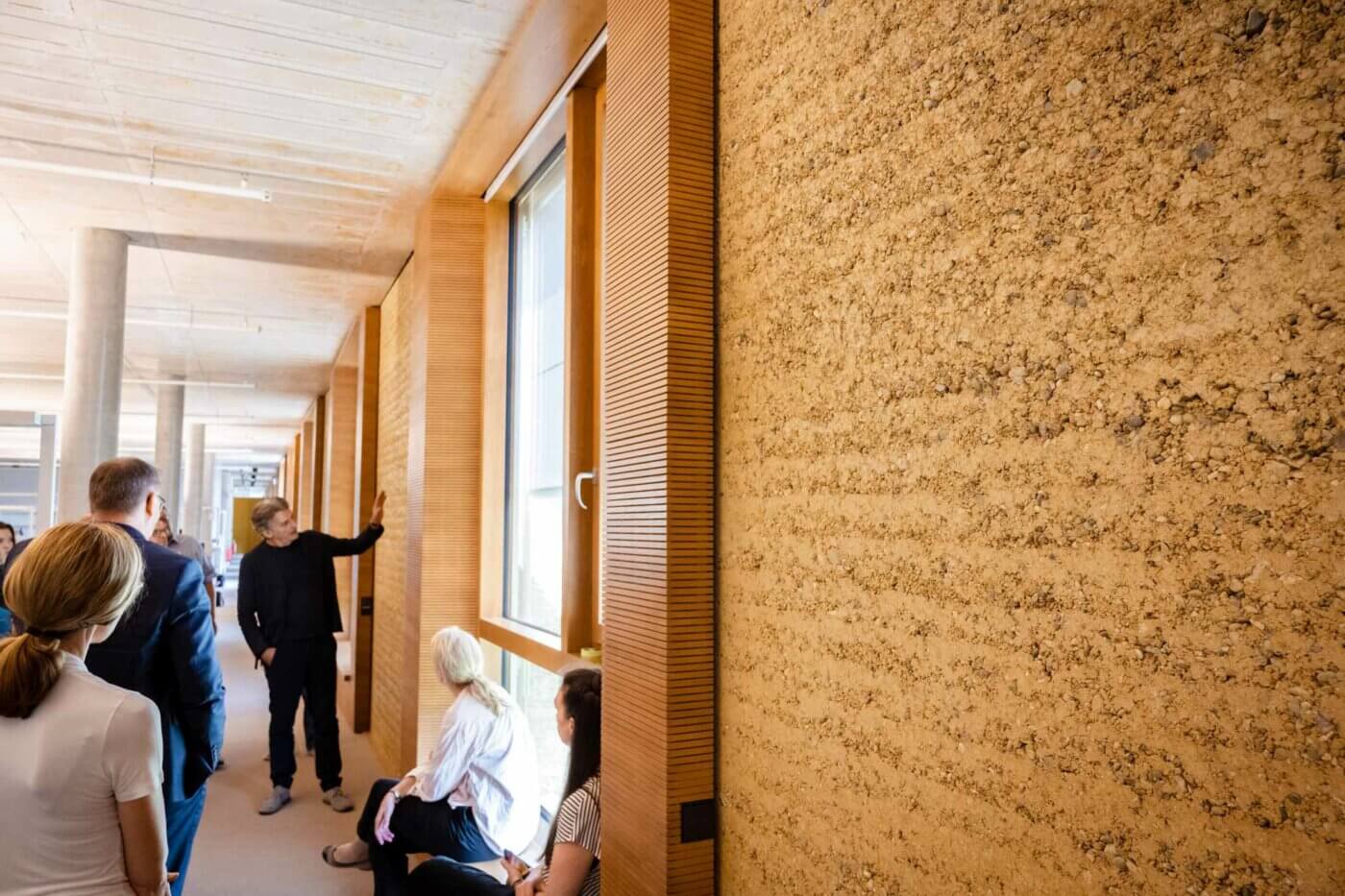 Auf der Führung über den Alnatura Campus zeigt Architekt Martin Haas der Gruppe die Lehmfassade. Foto: Andreas Reeg