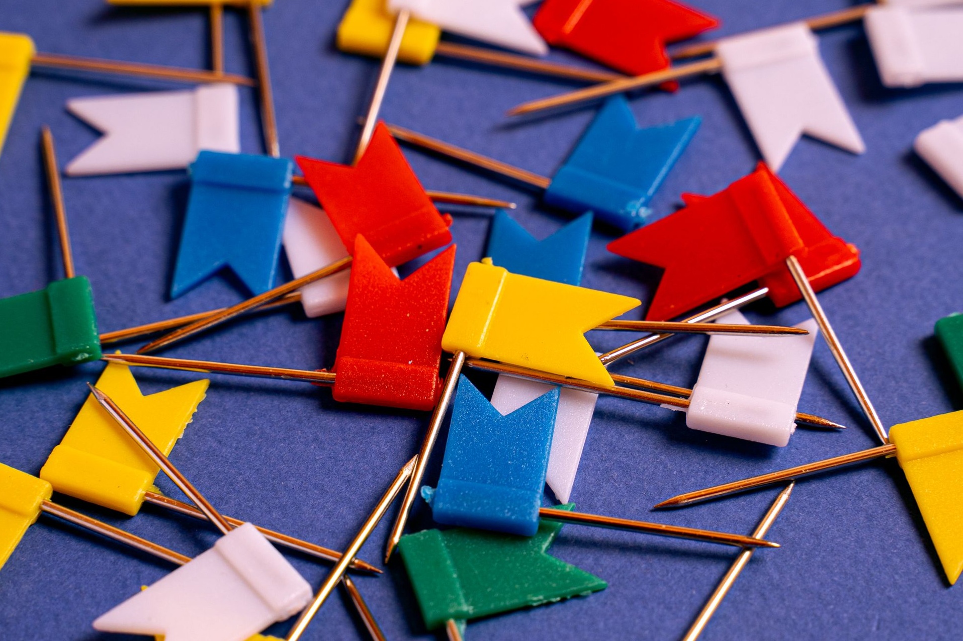 Auf dem Bild sieht man viele bunte Fähnchen mit Pin, die auf einer blauen Unterlage liegen. Copyright: pexels.com/AI25.Studio Studio